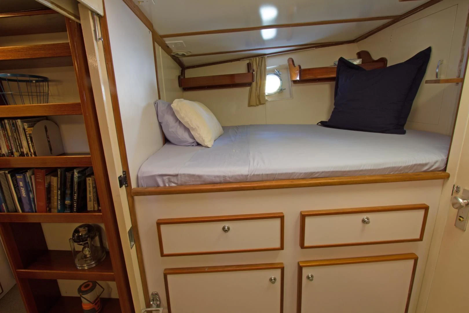 a bed with a blue pillow and a bookcase aboard SEA CZAR Yacht for Sale