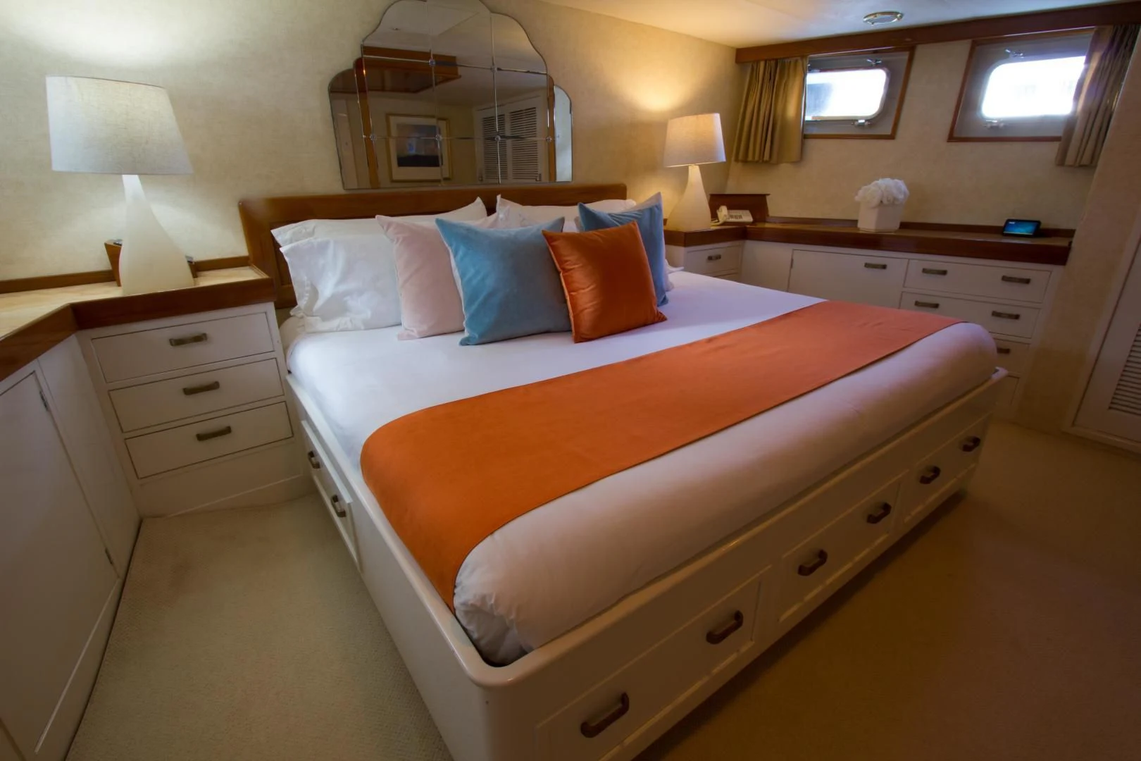 a bed with a white and orange pillow and a white dresser aboard SEA CZAR Yacht for Sale