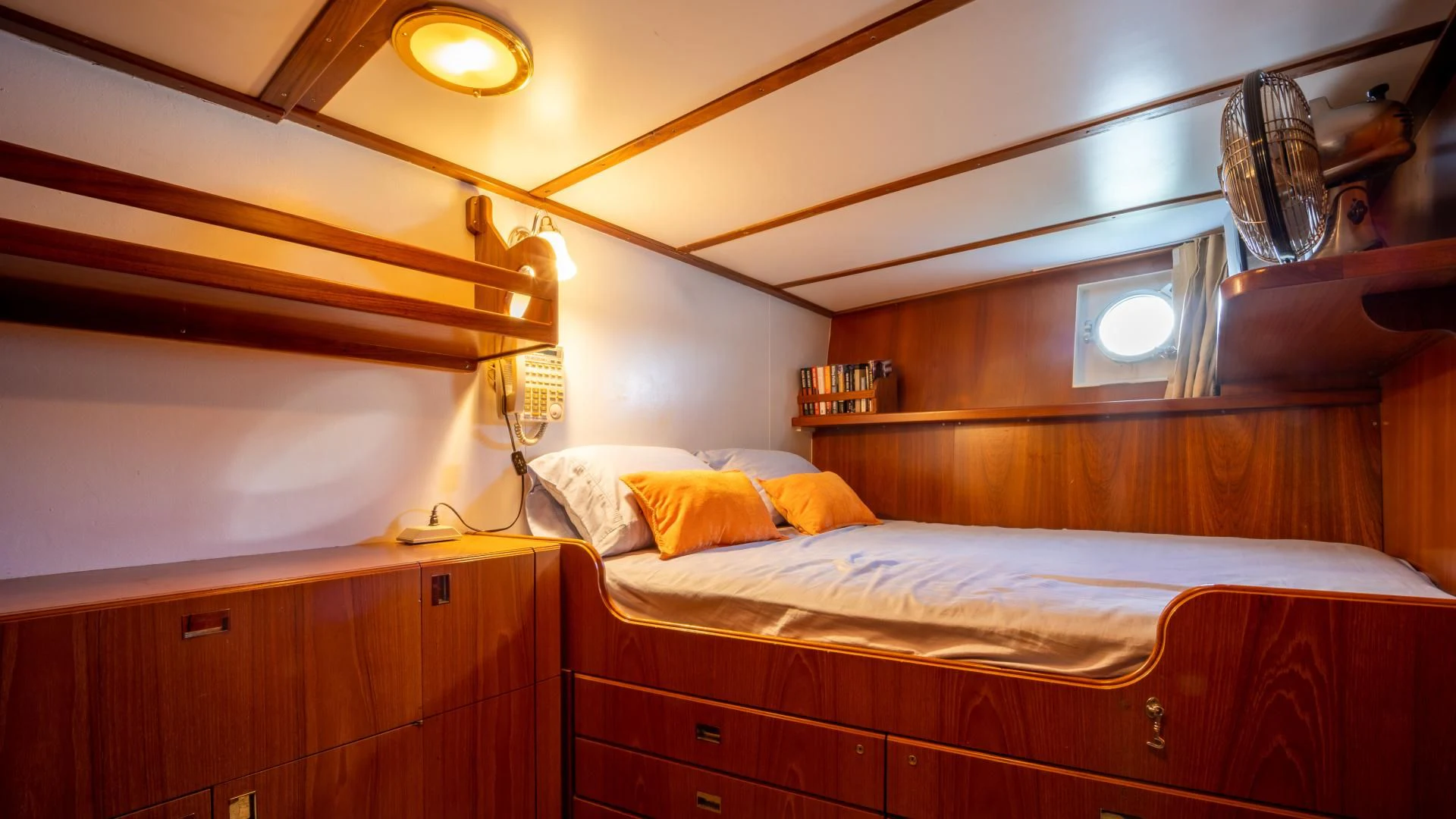 a room with a bed and a shelf with a lamp aboard SEA CZAR Yacht for Sale