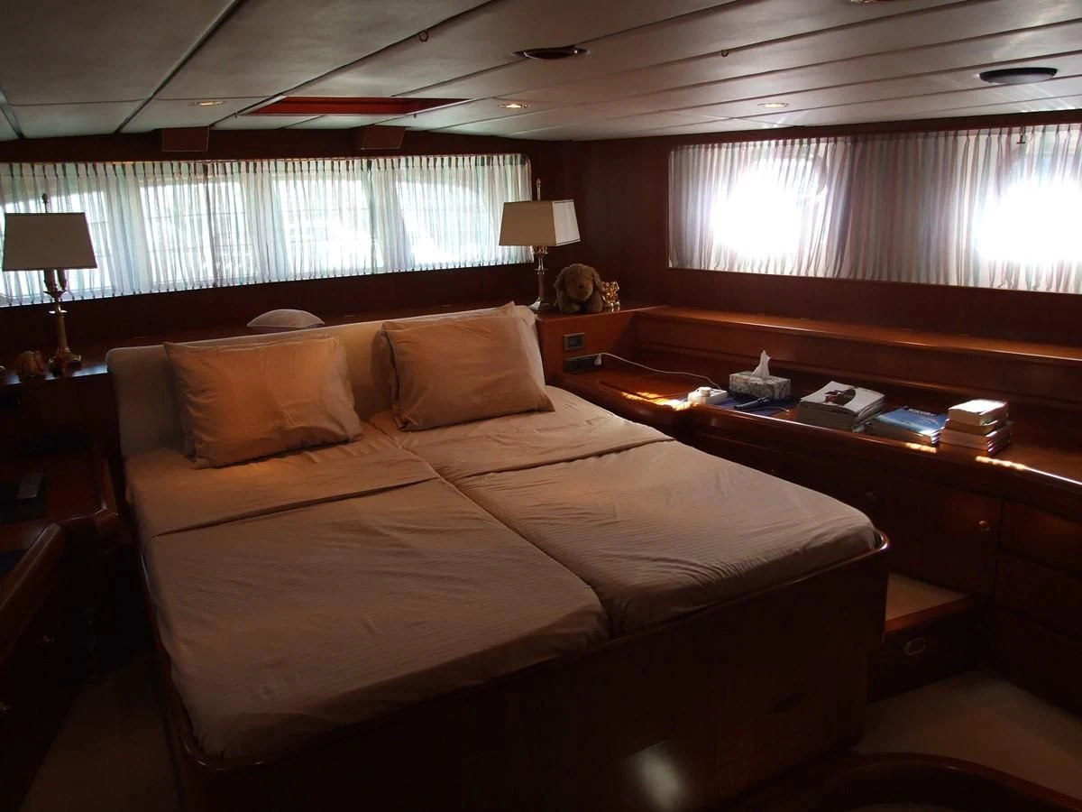 a bed with a desk and a window in the background aboard IMPRESSION Yacht for Sale