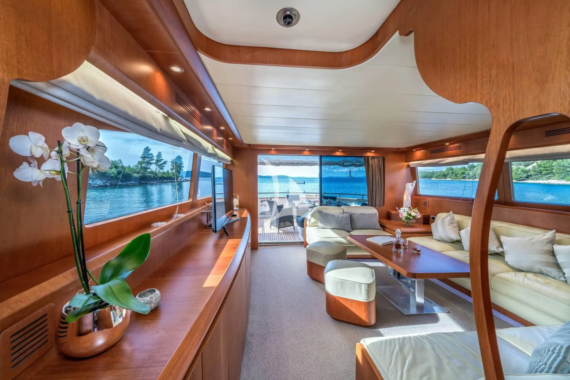 a room with a large window and a table with flowers in it aboard JANTAR Yacht for Charter