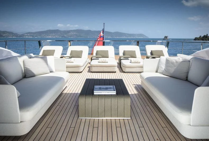 a deck with chairs and a flag on it aboard SEVEN SINS Yacht for Sale