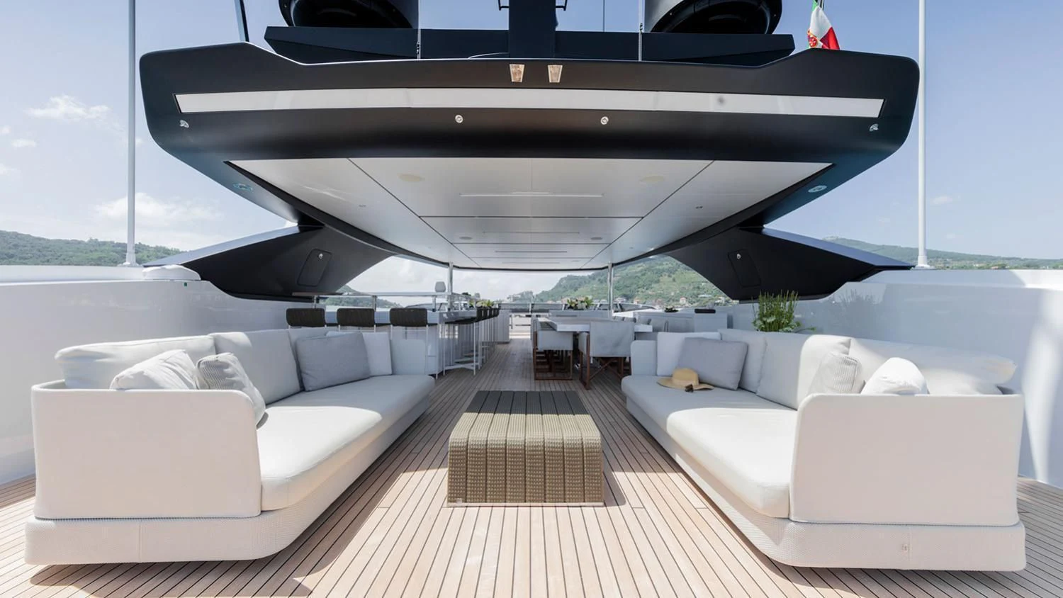 a deck with couches and a large boat in the background aboard SEVEN SINS Yacht for Sale