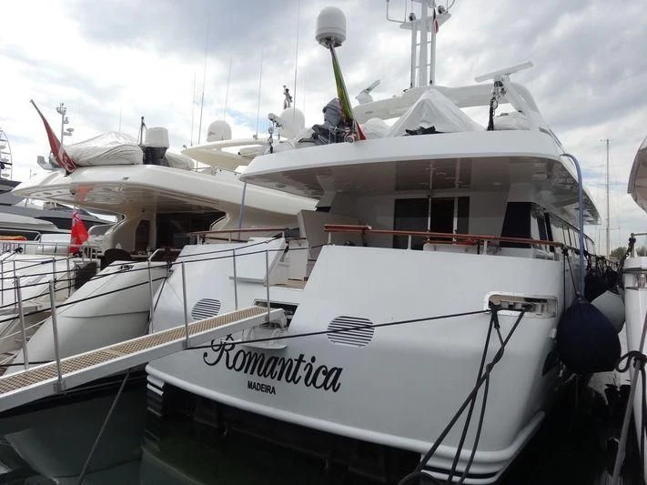 a white boat with a flag on it aboard ROMANTICA Yacht for Sale