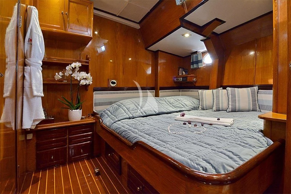 a bed with a white sheet and pillows in a room with wood walls aboard WIND OF CHANGE Yacht for Charter
