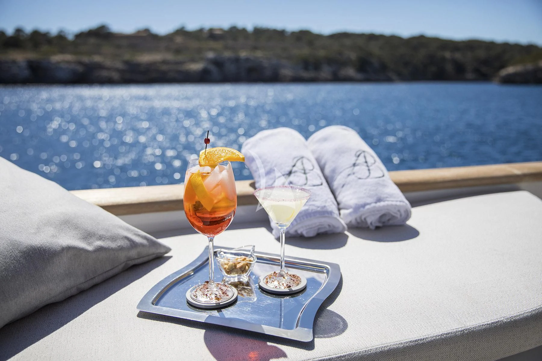 a couple of glasses of wine on a table with a beach in the background aboard ALWAYS BELIEVE Yacht for Sale
