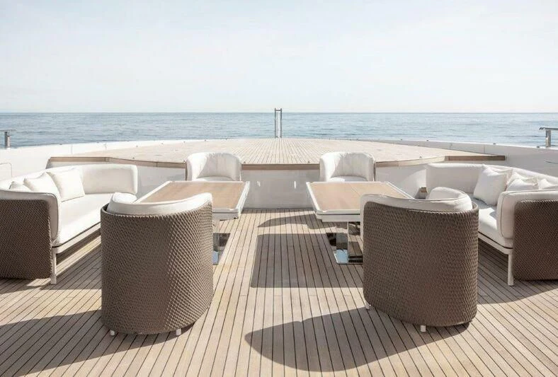 a deck with chairs and tables on it by the ocean aboard MY ALMA Yacht for Sale