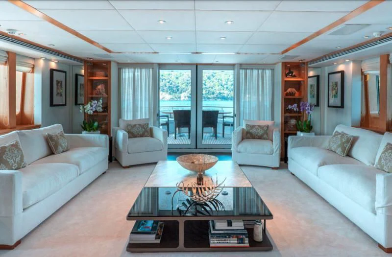 a living room with a glass coffee table and white couches aboard DEEP BLUE II Yacht for Charter