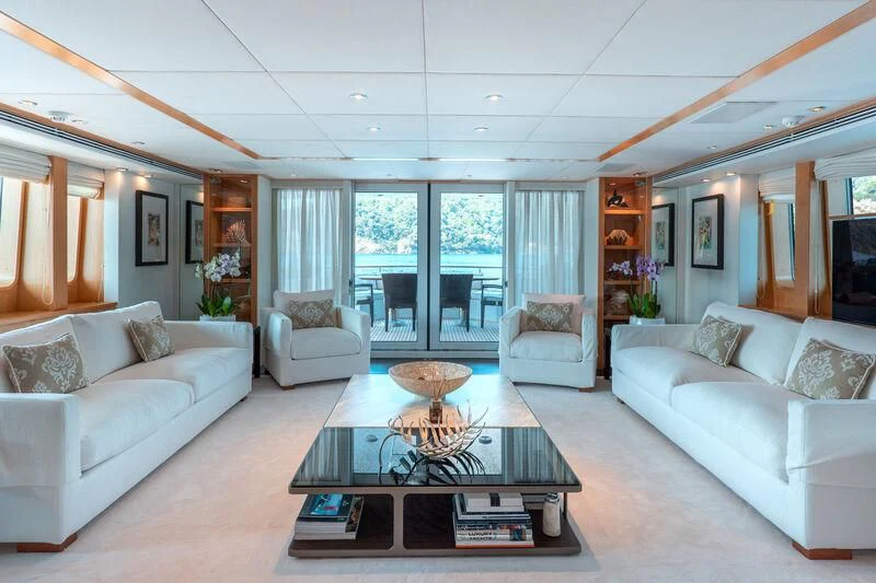 a living room with a glass coffee table and white couches aboard DEEP BLUE II Yacht for Charter