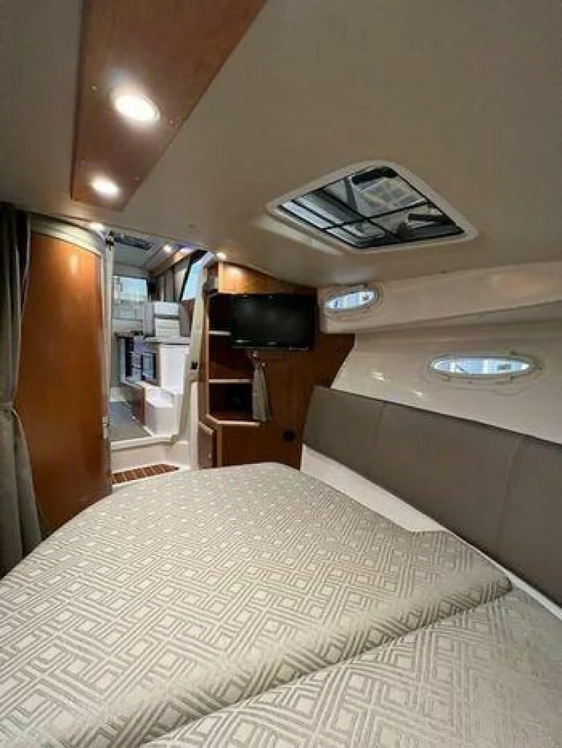 a bed with a white comforter and a television on it aboard SKYCHASER Yacht for Sale
