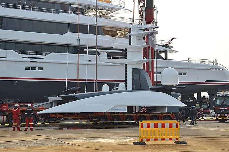 a large white boat sits in front of a large ship aboard SHODAN Yacht for Sale