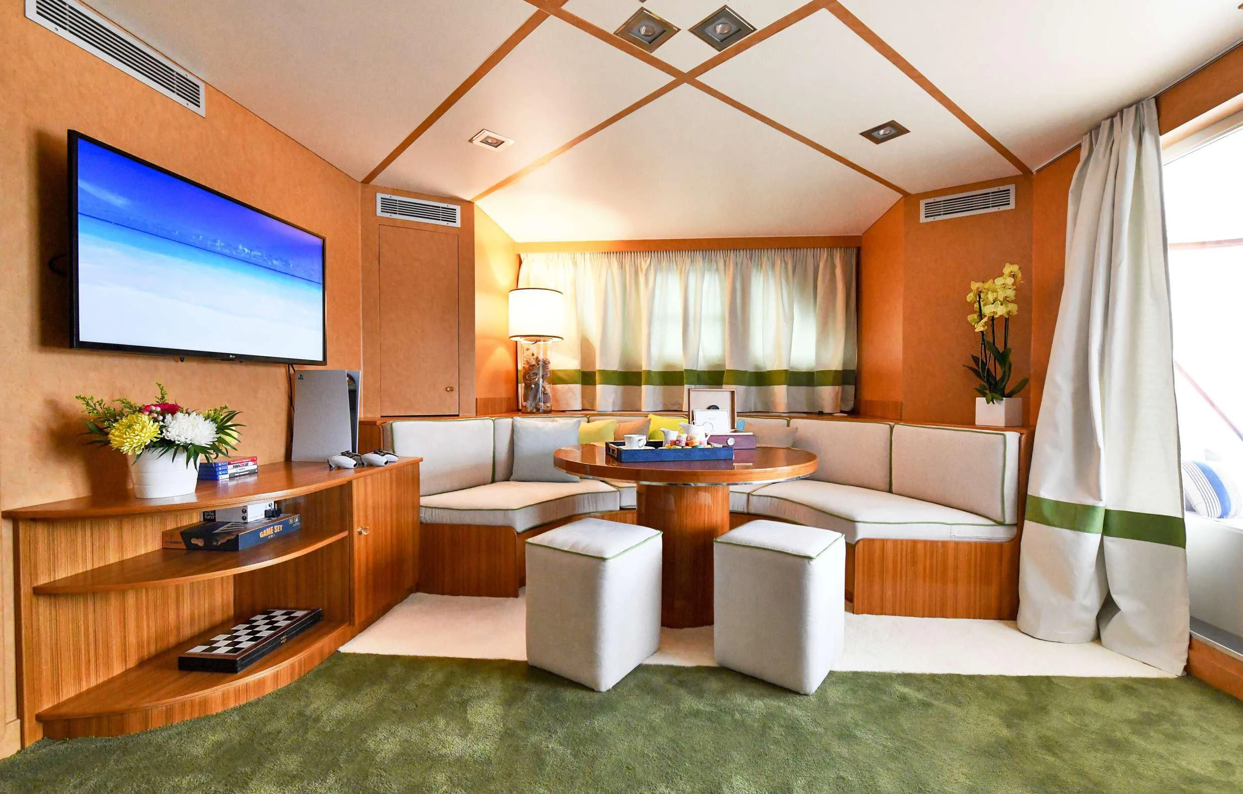 a living room with a tv and sofas aboard SOMETHING COOL Yacht for Charter
