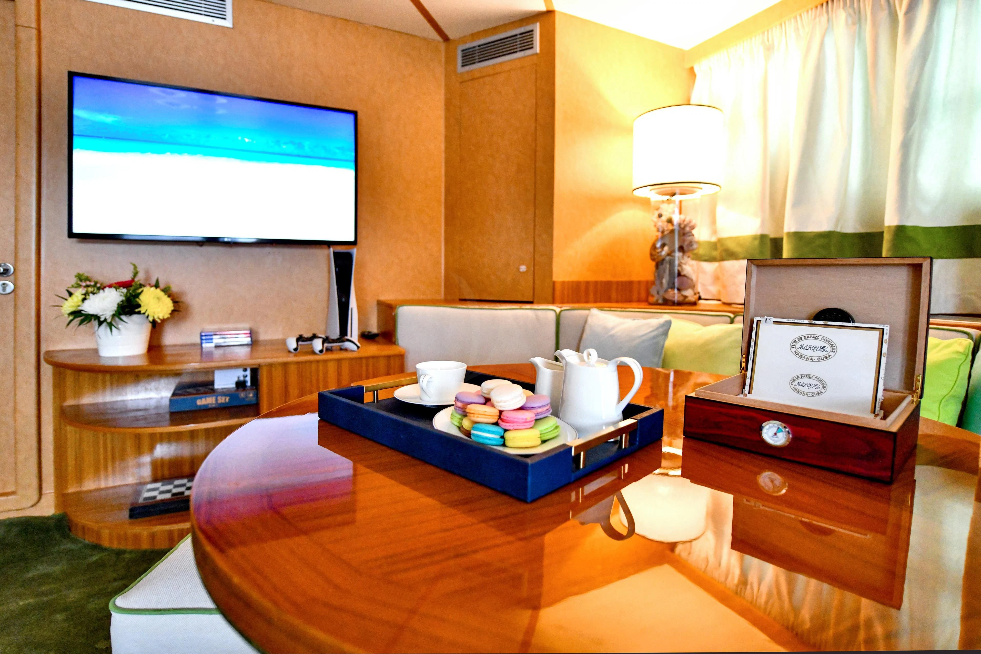 a room with a tv and a table with a couch aboard SOMETHING COOL Yacht for Charter