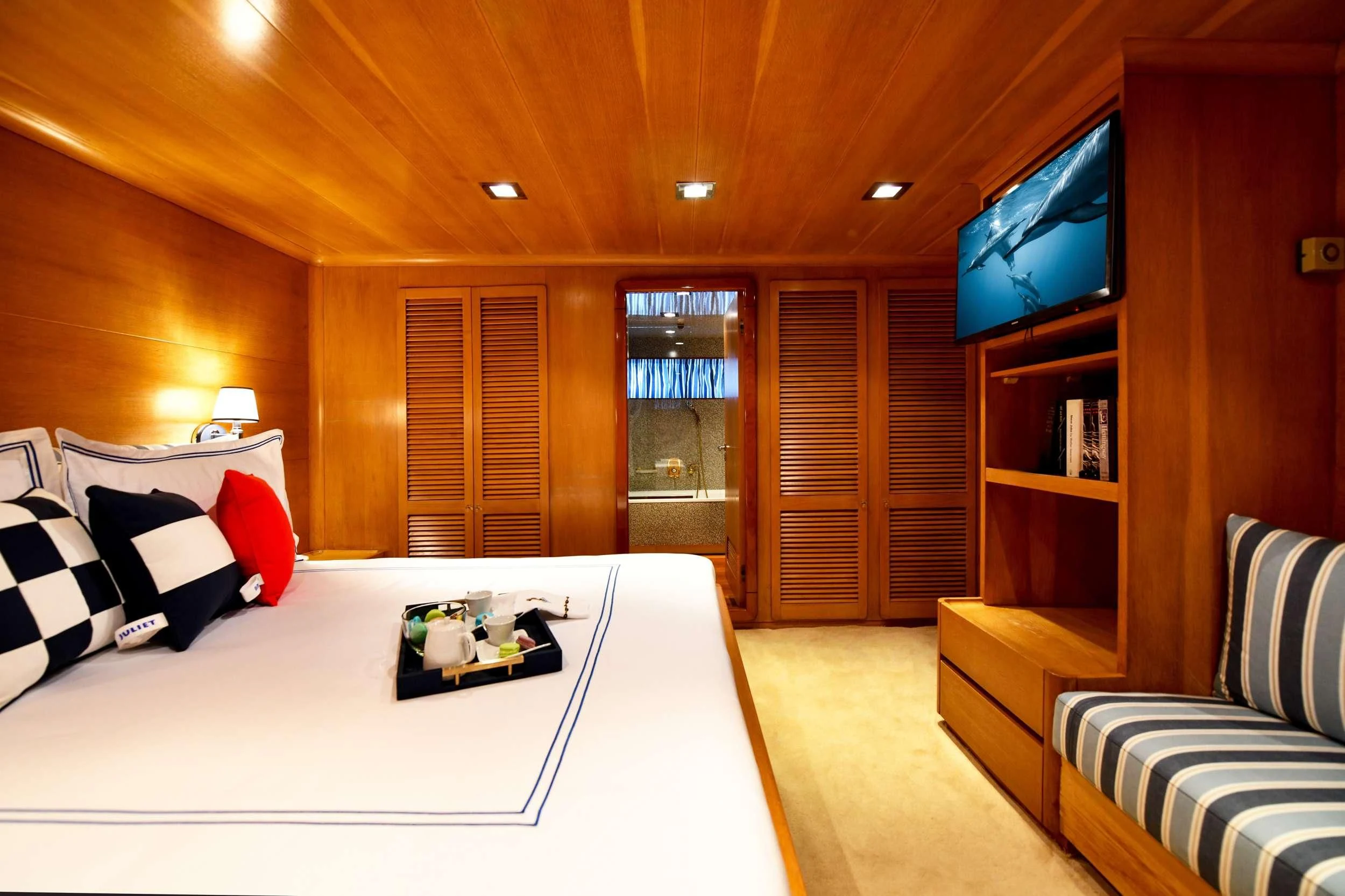 a room with a bed and a tv on the wall aboard SOMETHING COOL Yacht for Charter