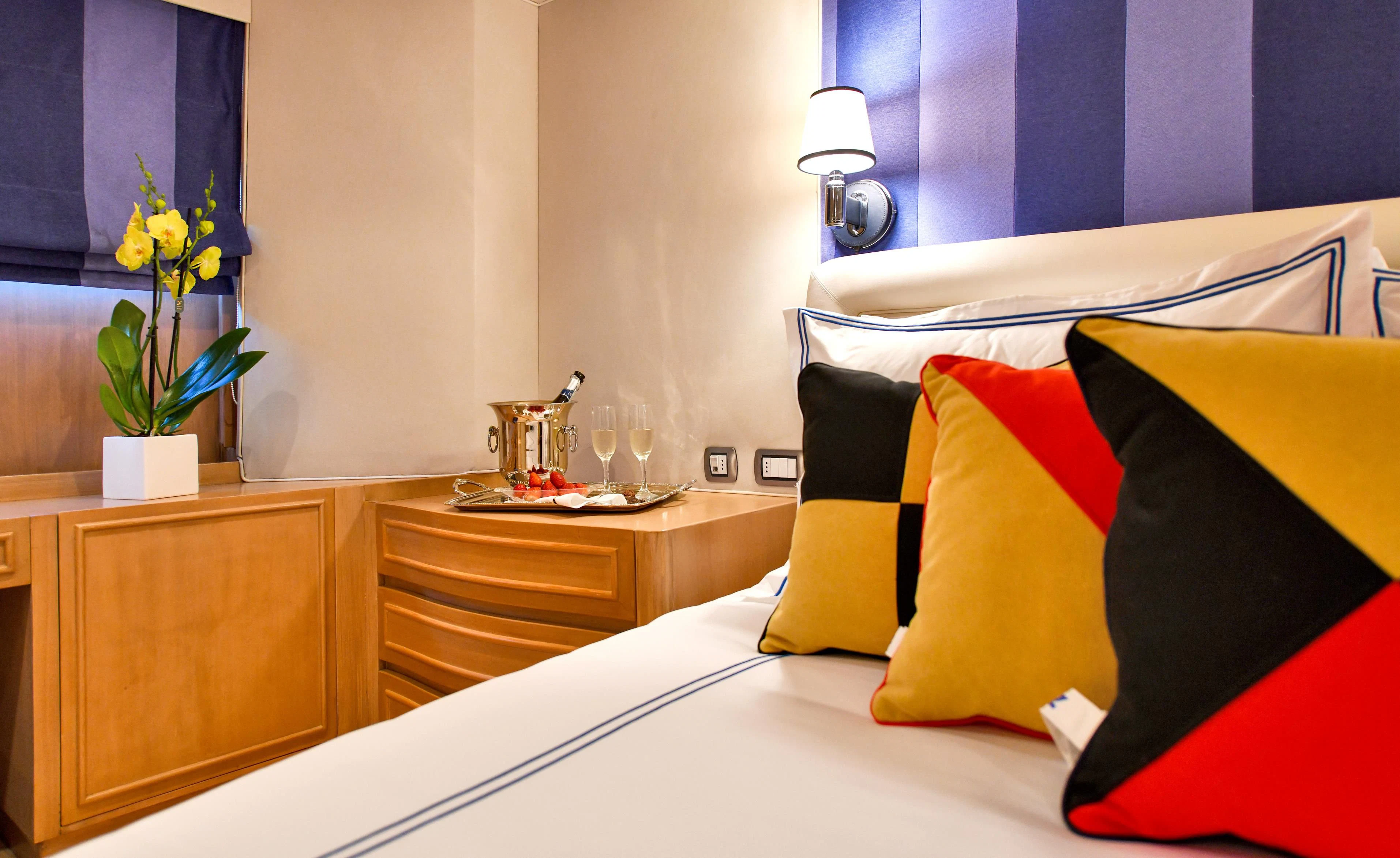 a bed with pillows and a lamp aboard SOMETHING COOL Yacht for Charter