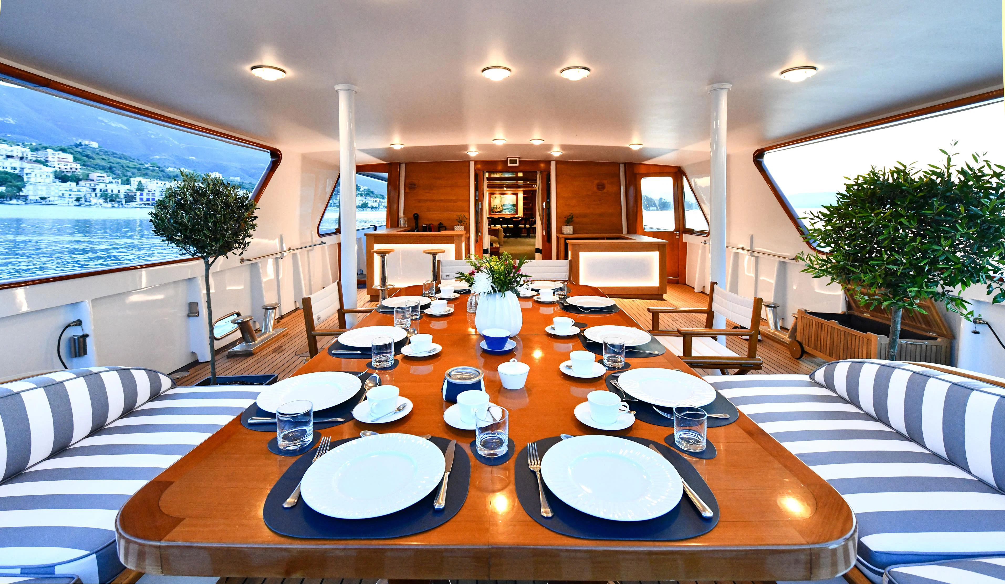 a large dining table with plates and chairs aboard SOMETHING COOL Yacht for Charter