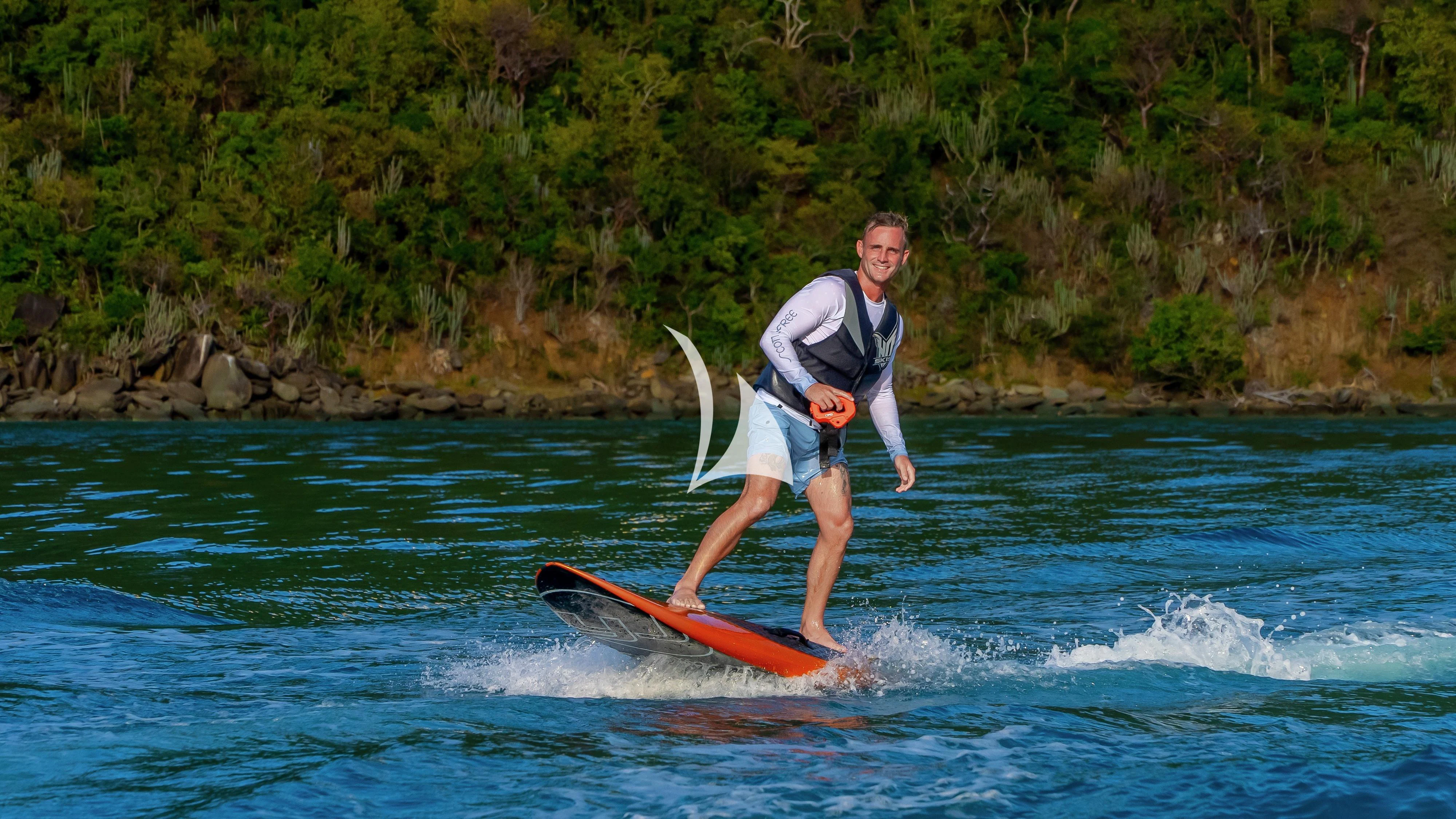 a man is surfing on the water aboard SCOTT FREE Yacht for Charter