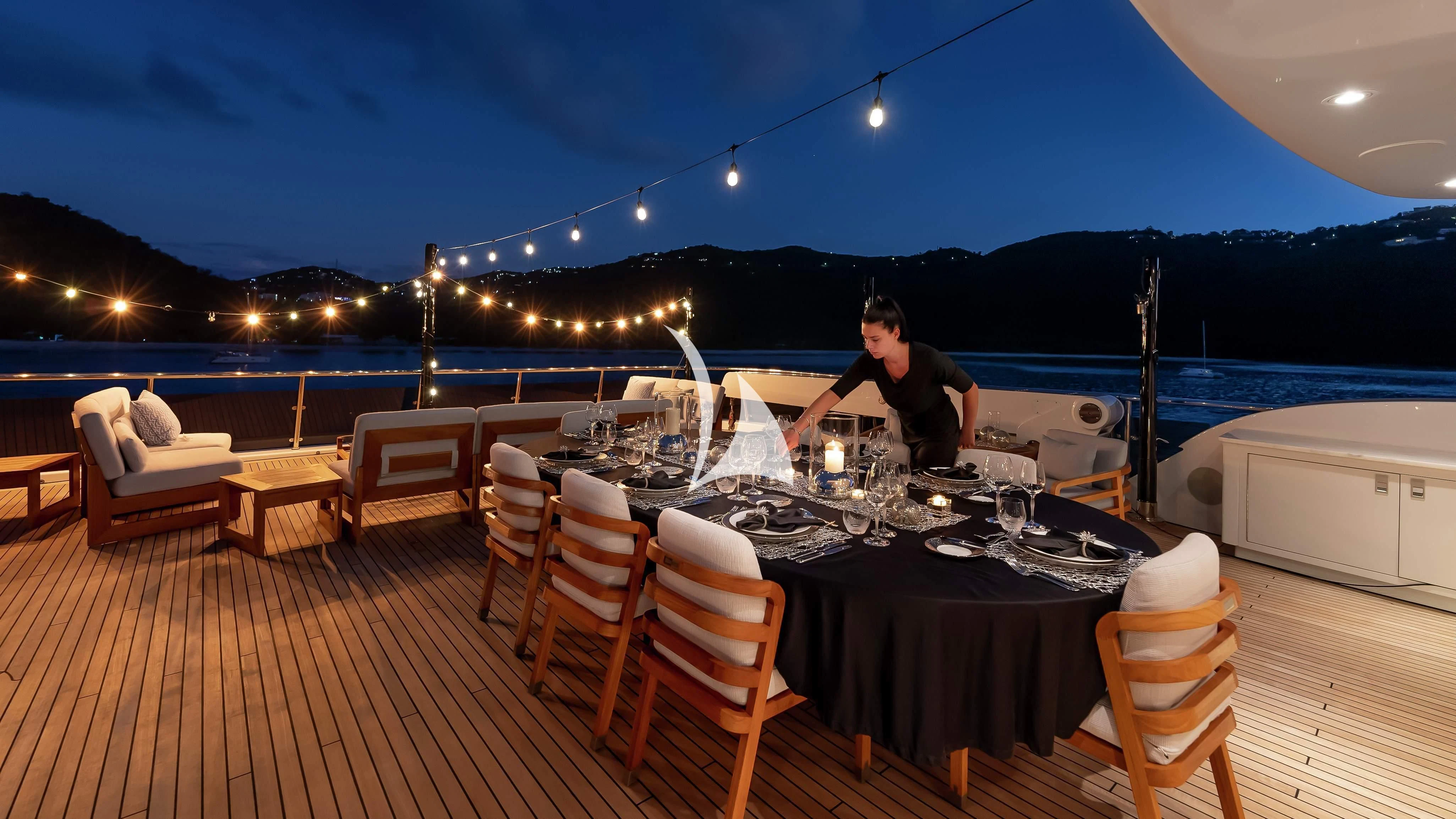 a person sitting at a table with a large body of water in the background aboard SCOTT FREE Yacht for Charter