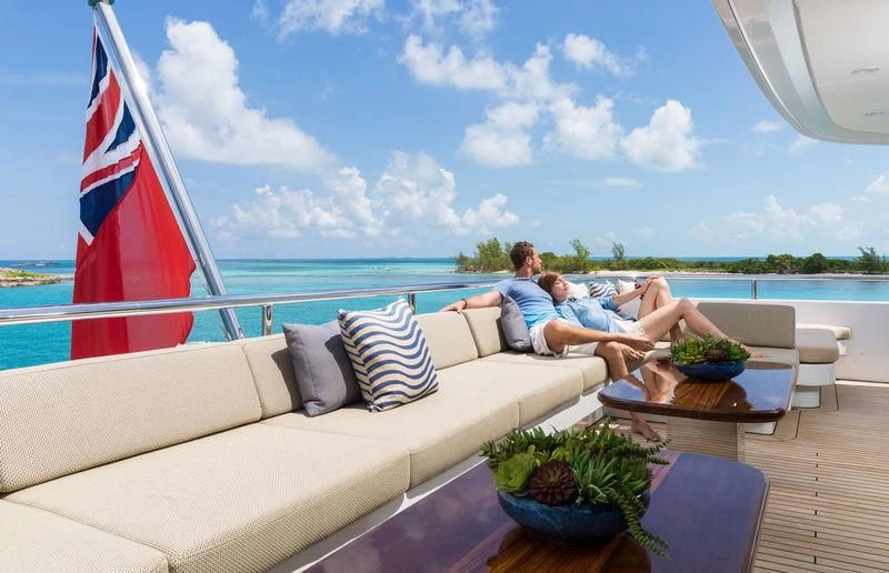 a couple sitting on a couch on a deck overlooking a large body of water aboard SCOTT FREE Yacht for Charter
