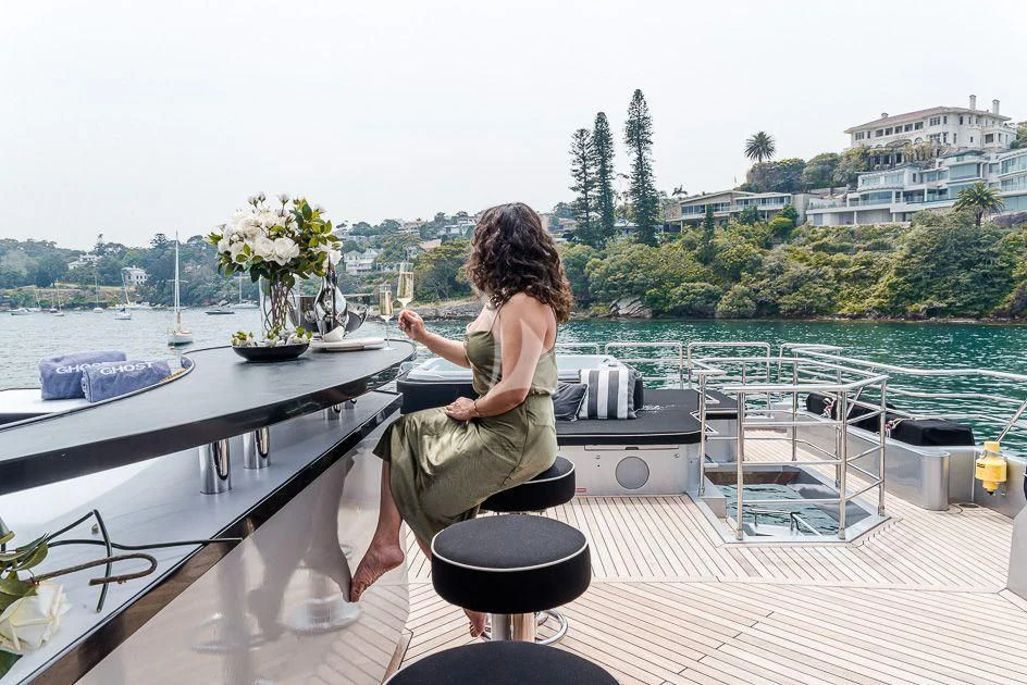 a person sitting on a table on a deck overlooking a body of water aboard GHOST II Yacht for Sale