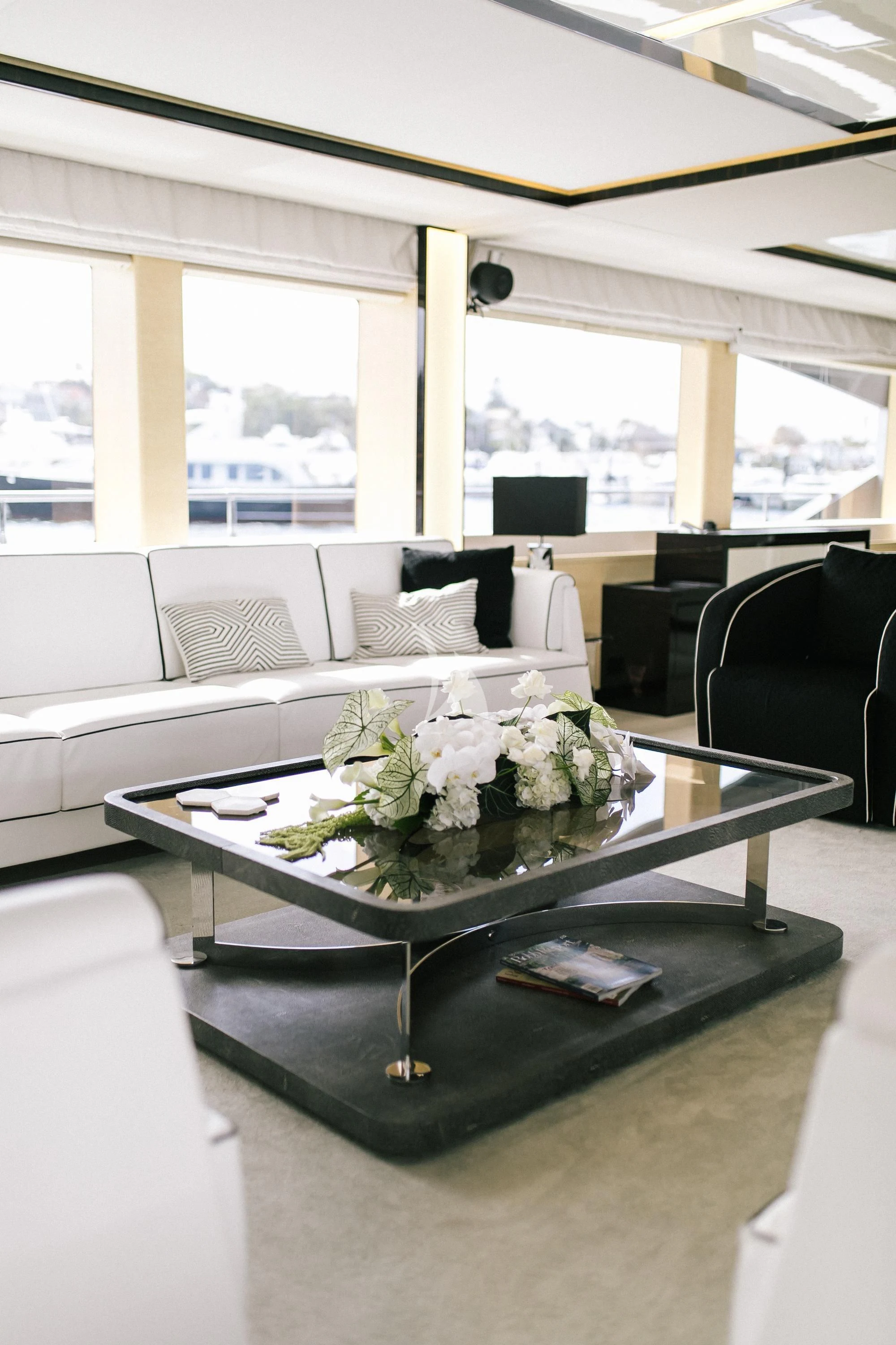 a glass coffee table with white flowers on it aboard GHOST II Yacht for Sale