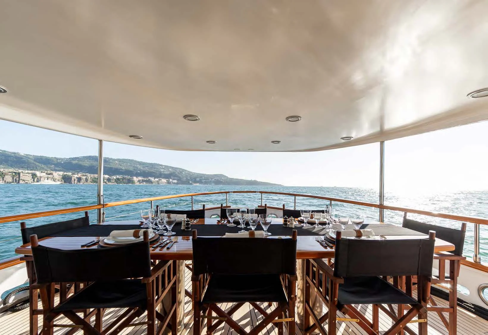 a table and chairs on a deck overlooking a large body of water aboard SOUNION II Yacht for Sale