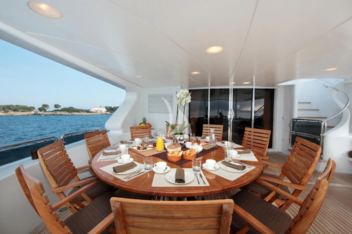 a dining table with chairs and a view of the water aboard INOUIS Yacht for Charter