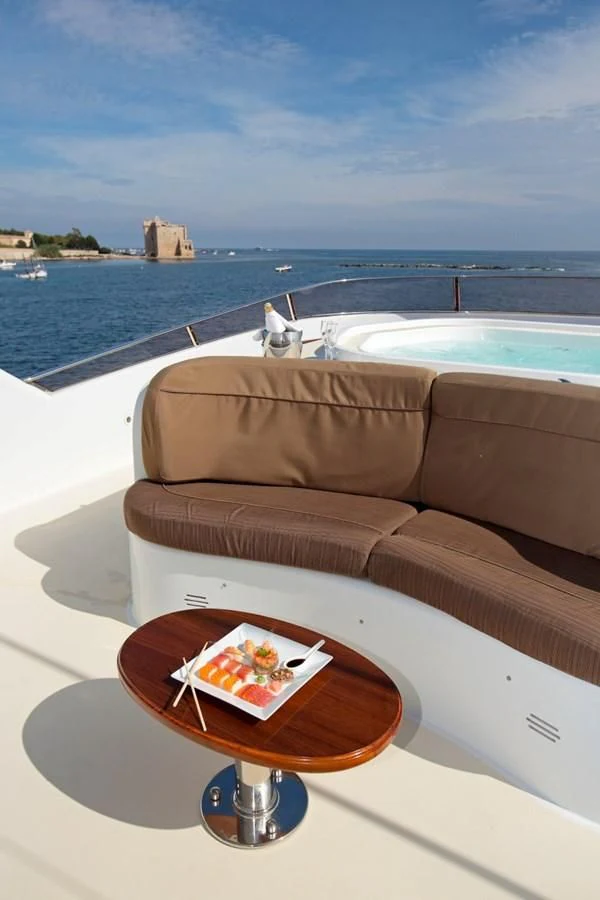 a coffee table on a balcony overlooking a body of water aboard INOUIS Yacht for Charter
