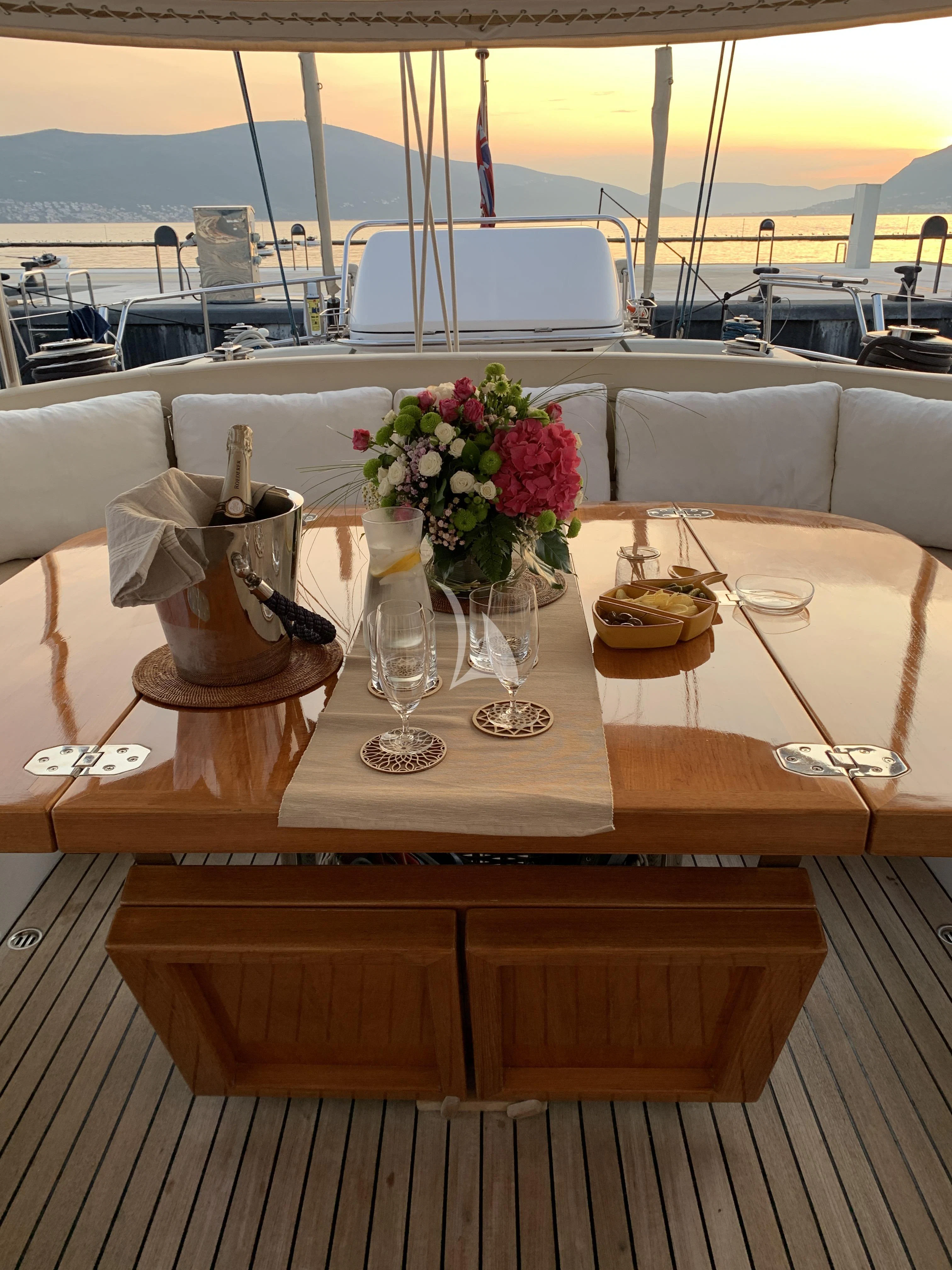 a table with a vase of flowers and a glass of wine on it aboard SONGBIRD OF LONDON Yacht for Sale