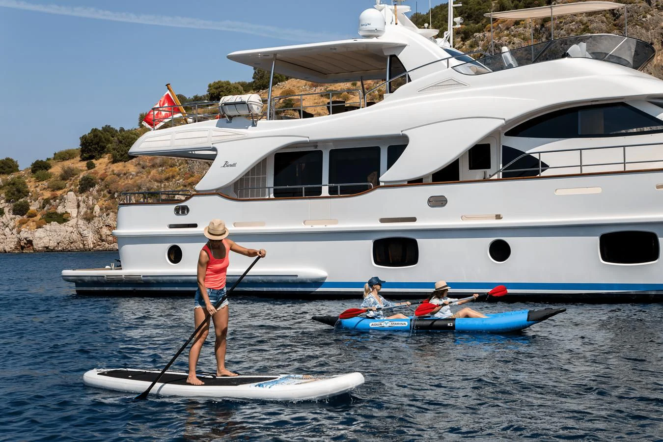 a person on a paddle board next to a boat aboard REBECCA V Yacht for Sale