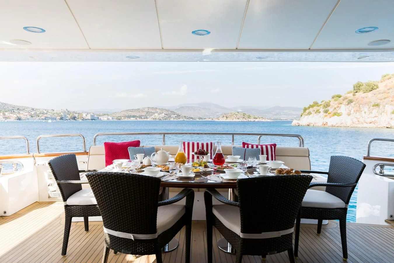 a table set for a meal on a balcony overlooking a large body of water aboard REBECCA V Yacht for Sale