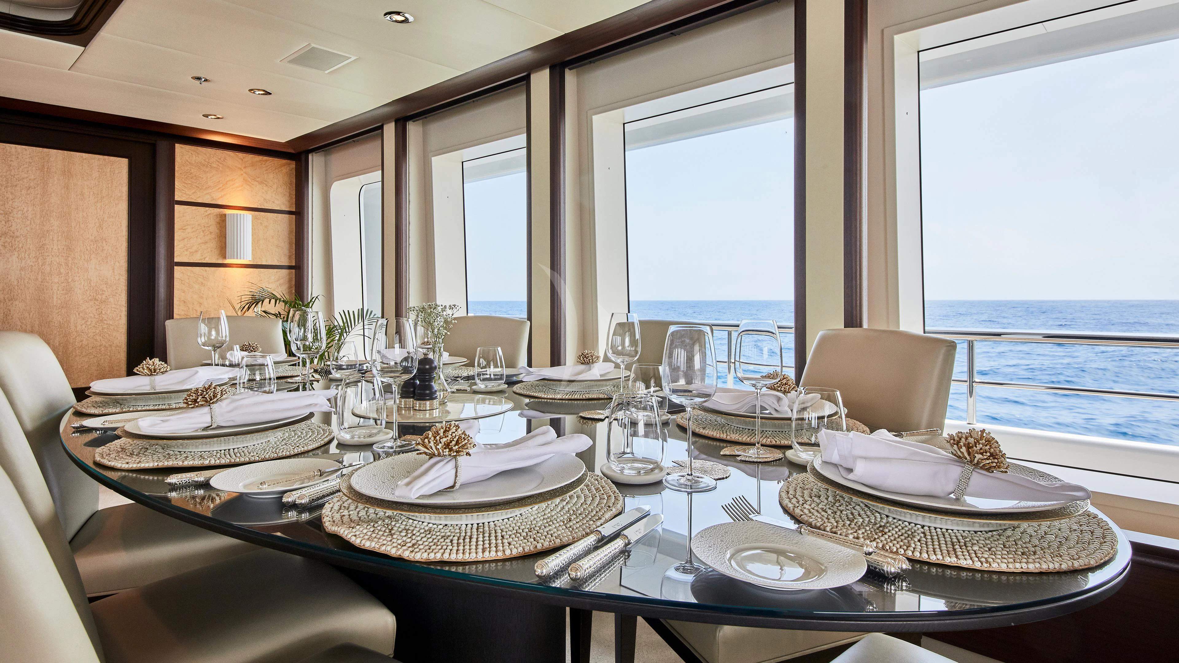 a dining room table with plates and glasses aboard GLADIATOR Yacht for Sale