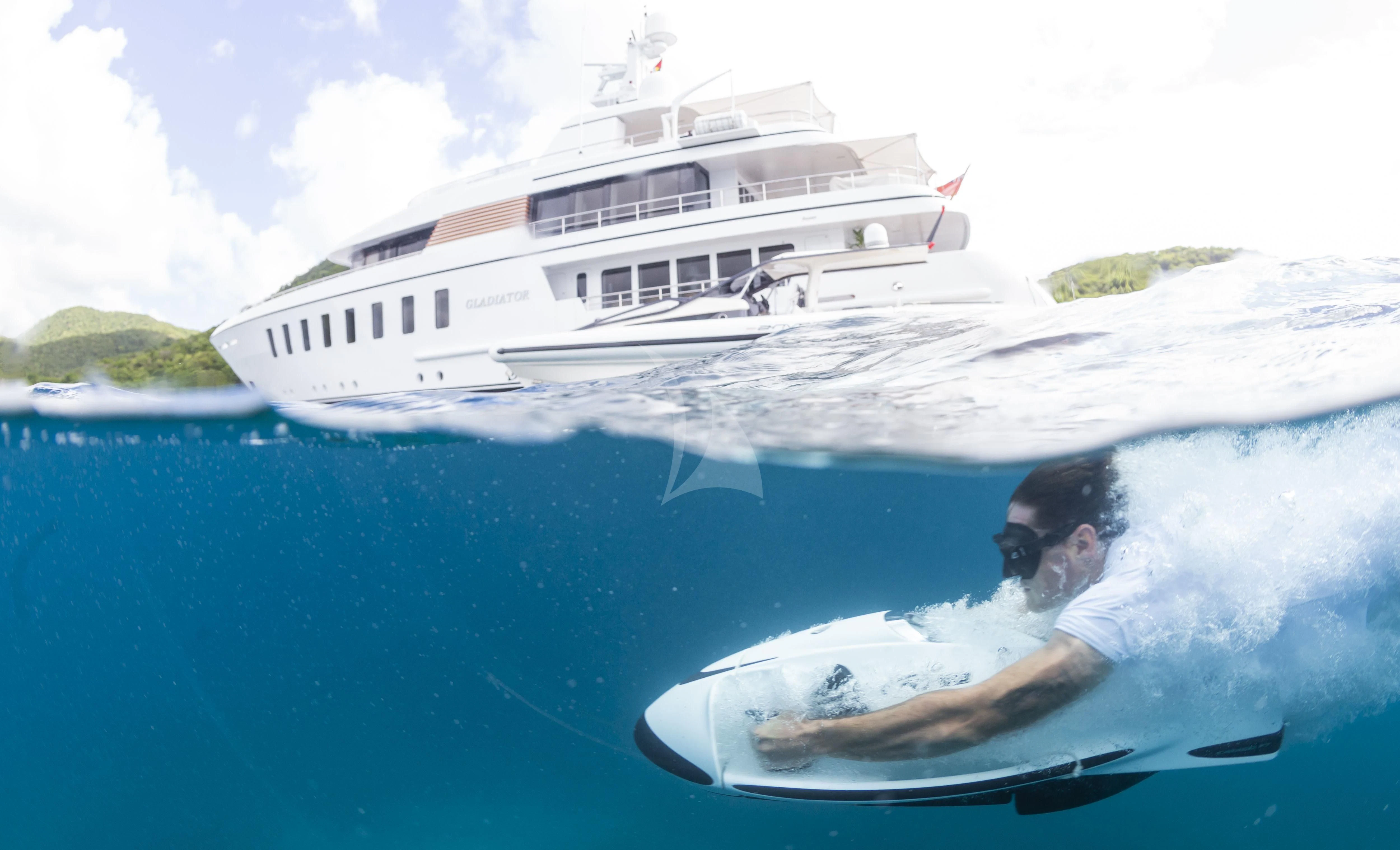 a man on a surfboard in the water with a boat in the background aboard GLADIATOR Yacht for Sale