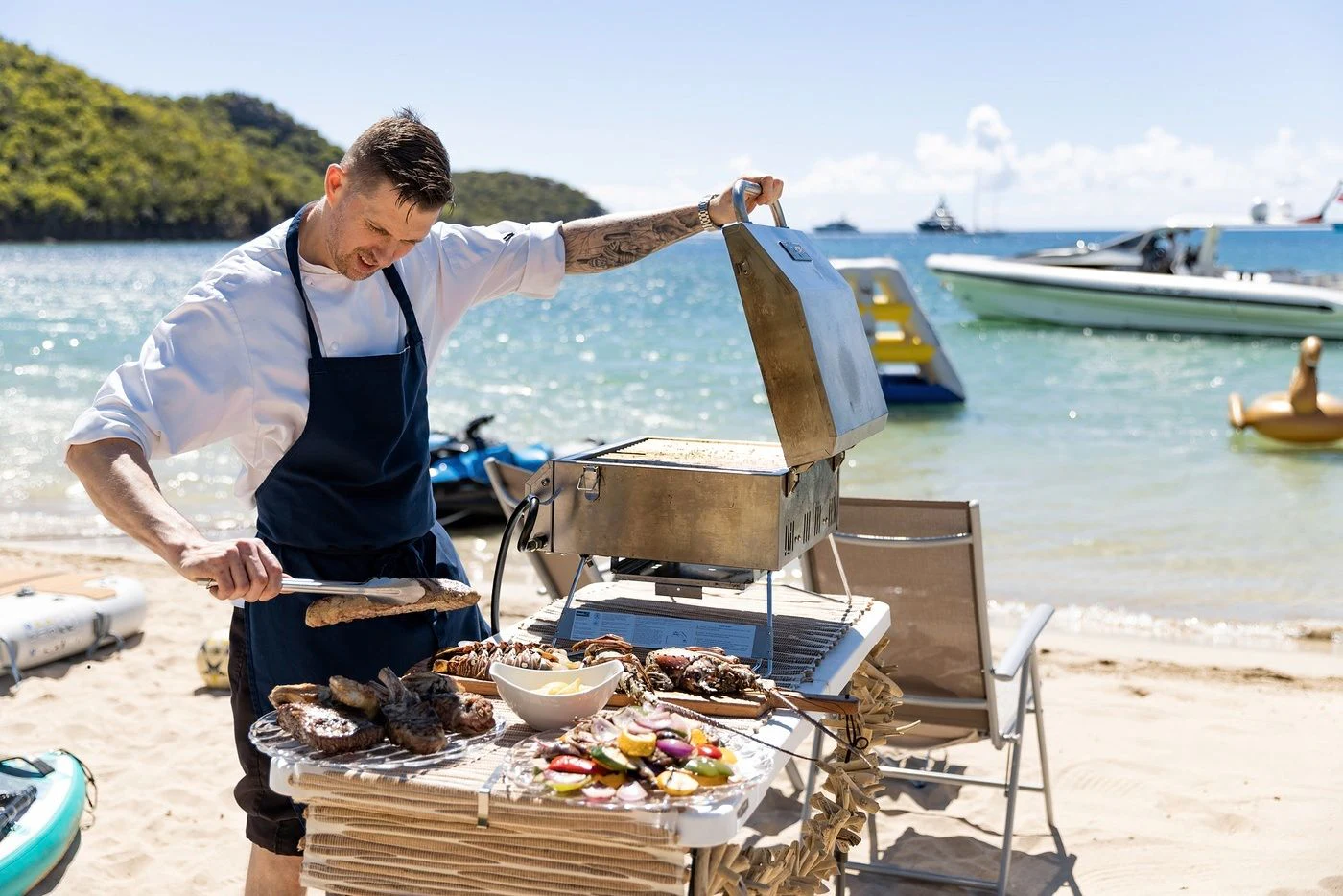 a man grilling fish on a beach aboard GLADIATOR Yacht for Sale
