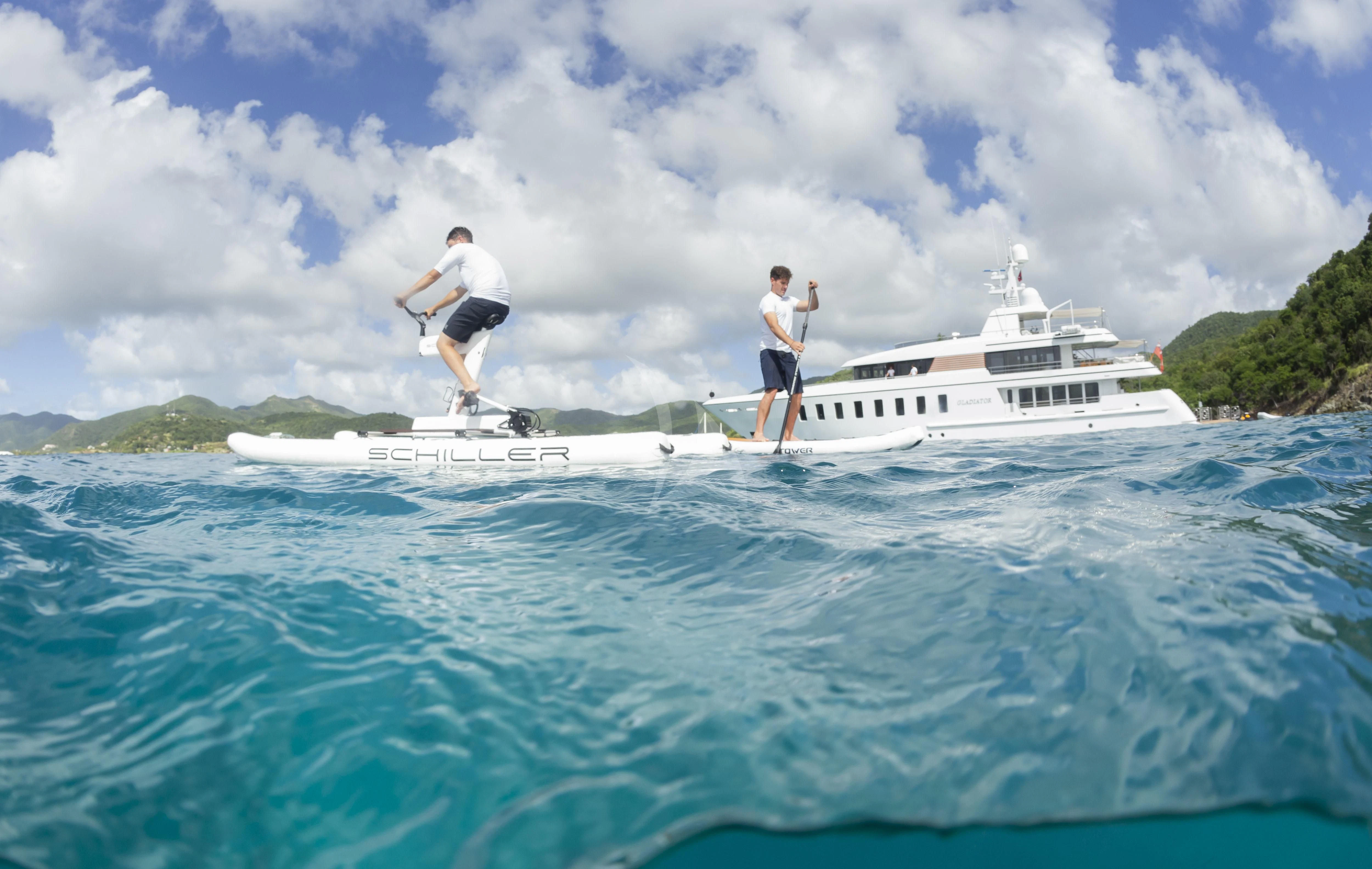two men jumping into a body of water with a boat in the background aboard GLADIATOR Yacht for Sale