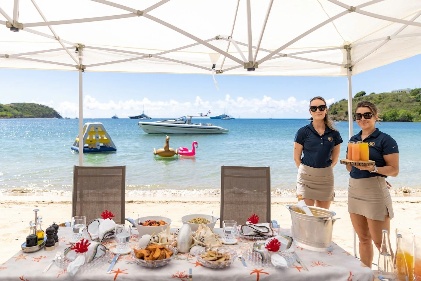 a couple of women standing by a table with food and drinks on it aboard GLADIATOR Yacht for Sale