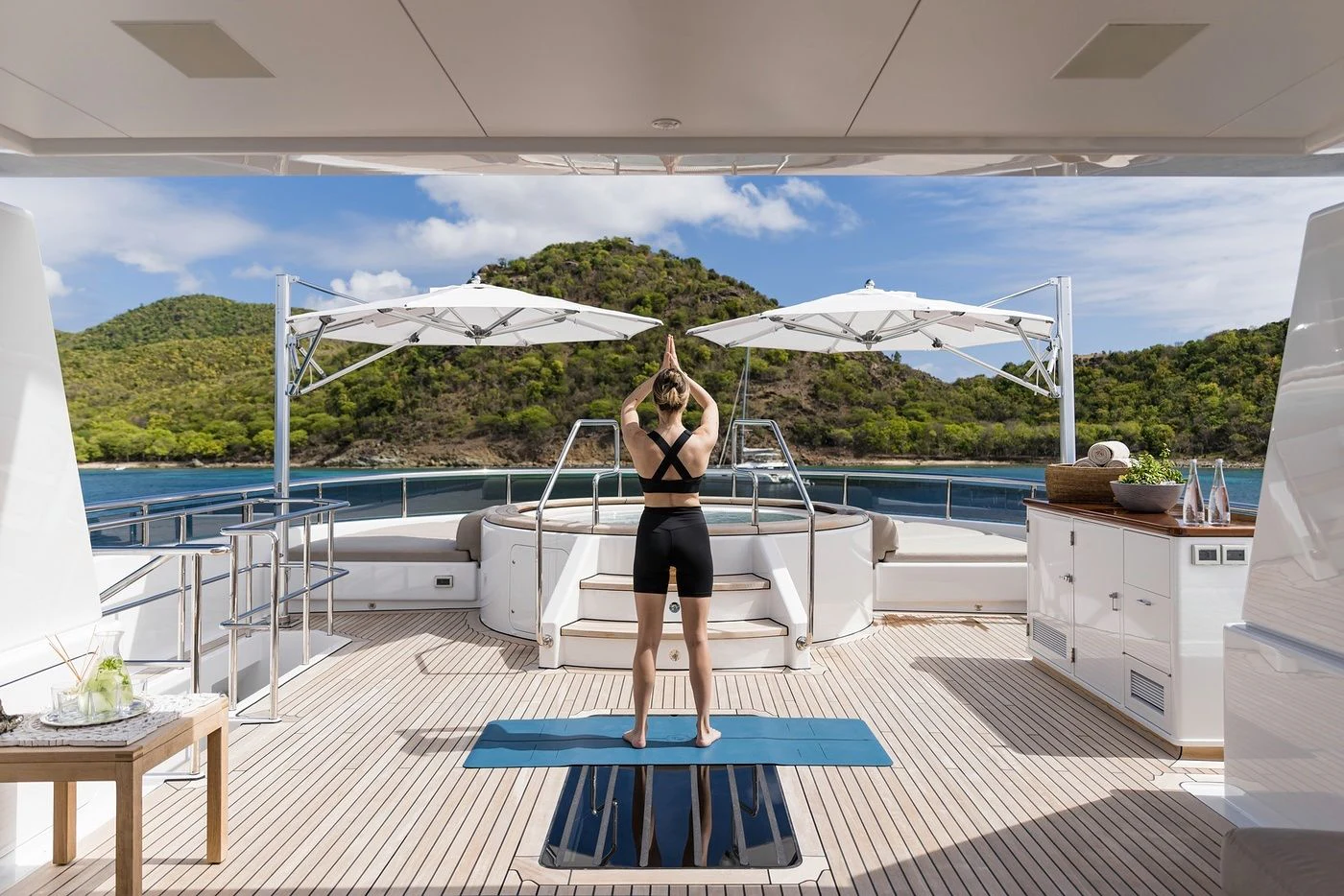 a person standing on a mat on a deck with a pool and a building in the background aboard GLADIATOR Yacht for Sale