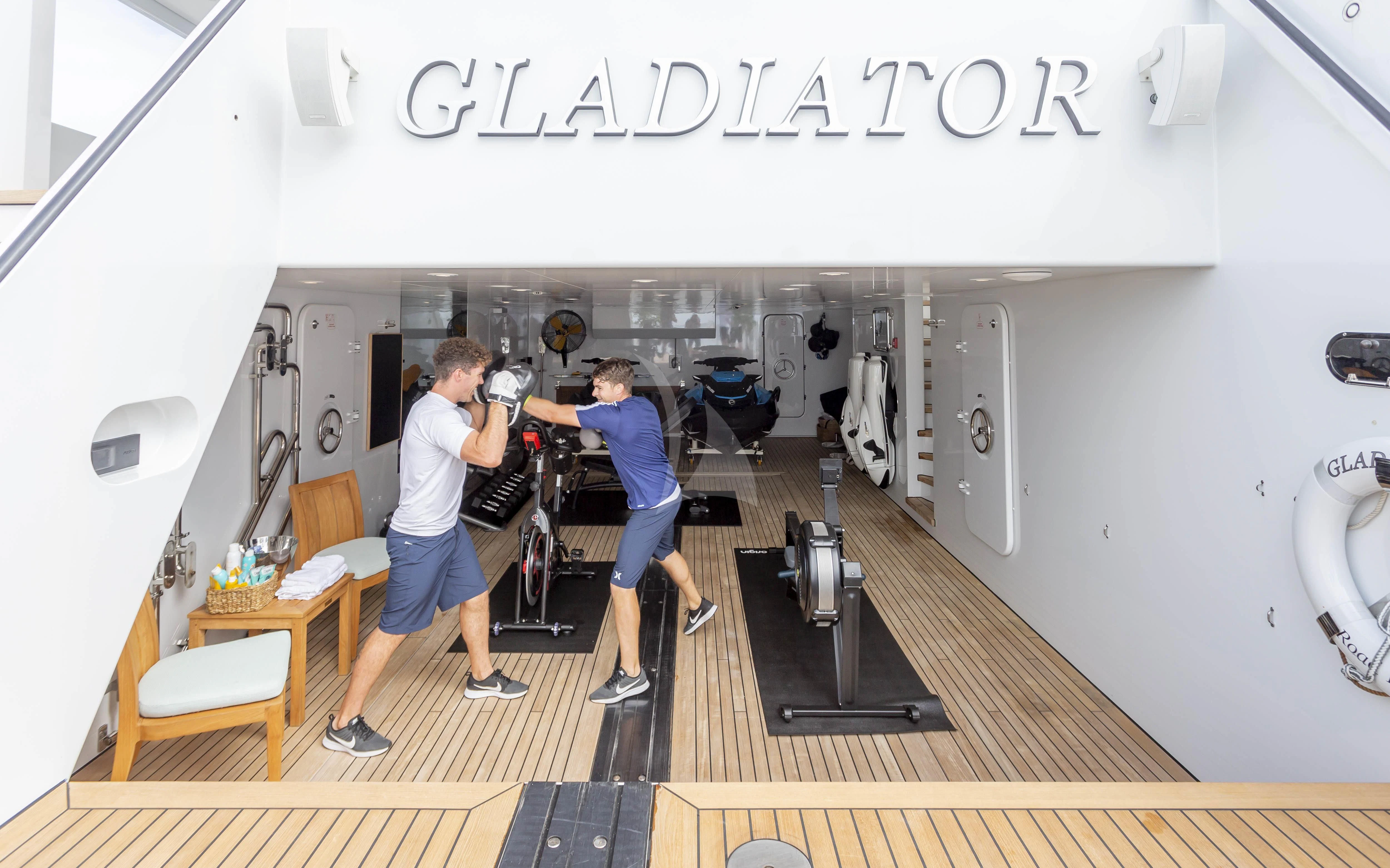 a group of people standing in a room with a black counter and chairs aboard GLADIATOR Yacht for Sale