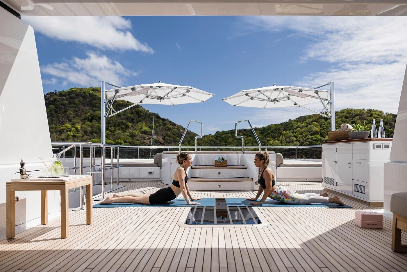 a couple of women sitting on a deck with a large white umbrella aboard GLADIATOR Yacht for Sale