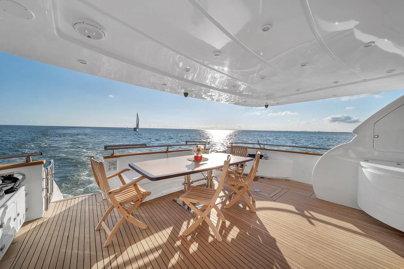 a deck with a table and chairs on it by the ocean aboard DOMINIC Yacht for Sale