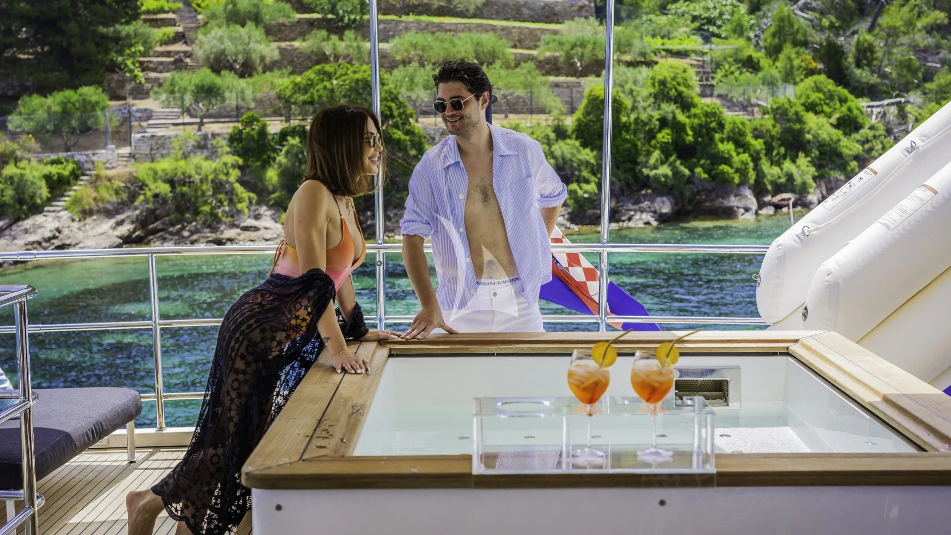 a man and woman sitting on a boat with drinks and a woman standing next to them aboard OCEAN DRIVE Yacht for Charter