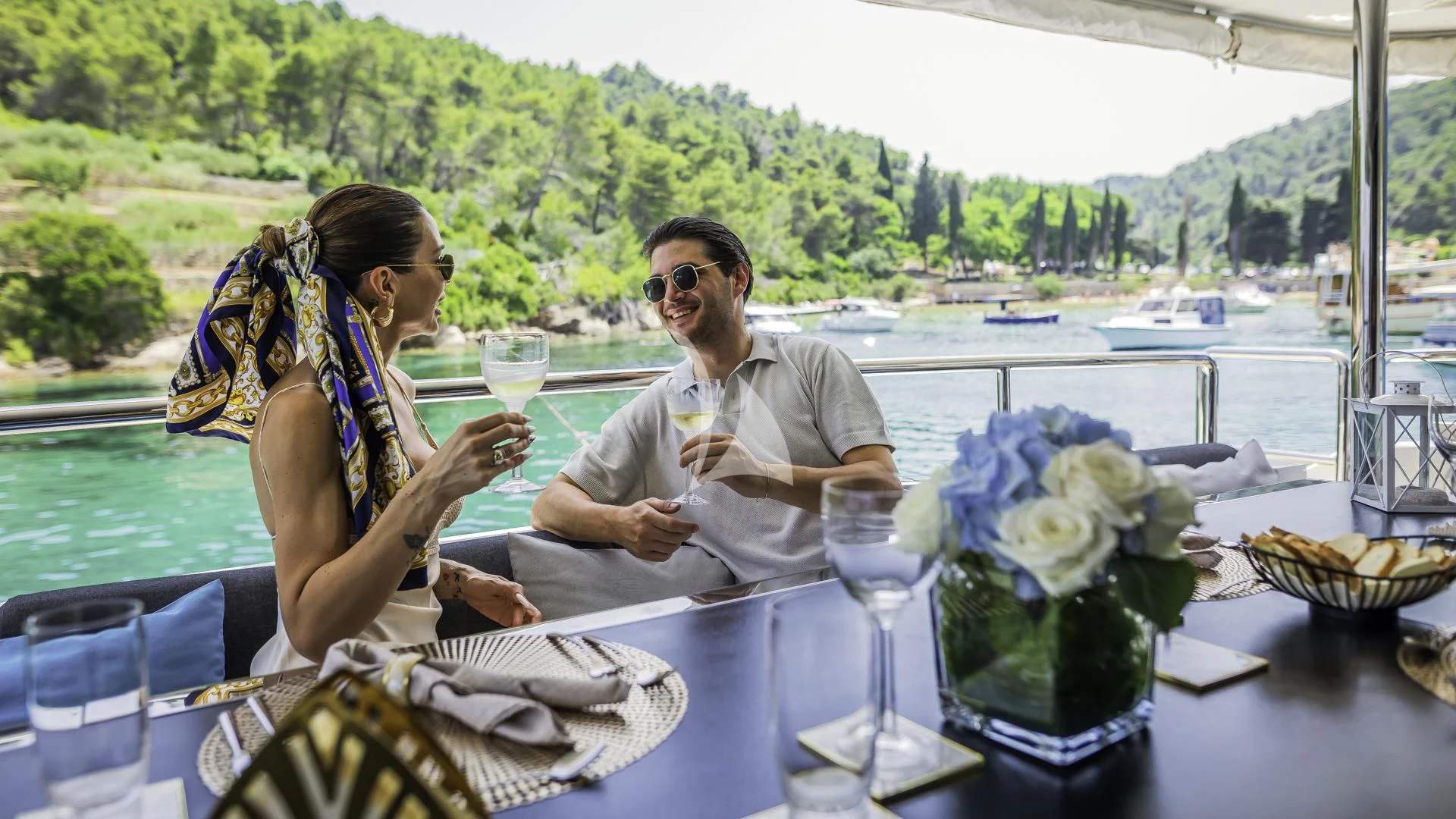 a man and a woman sitting at a table with drinks on it aboard OCEAN DRIVE Yacht for Charter