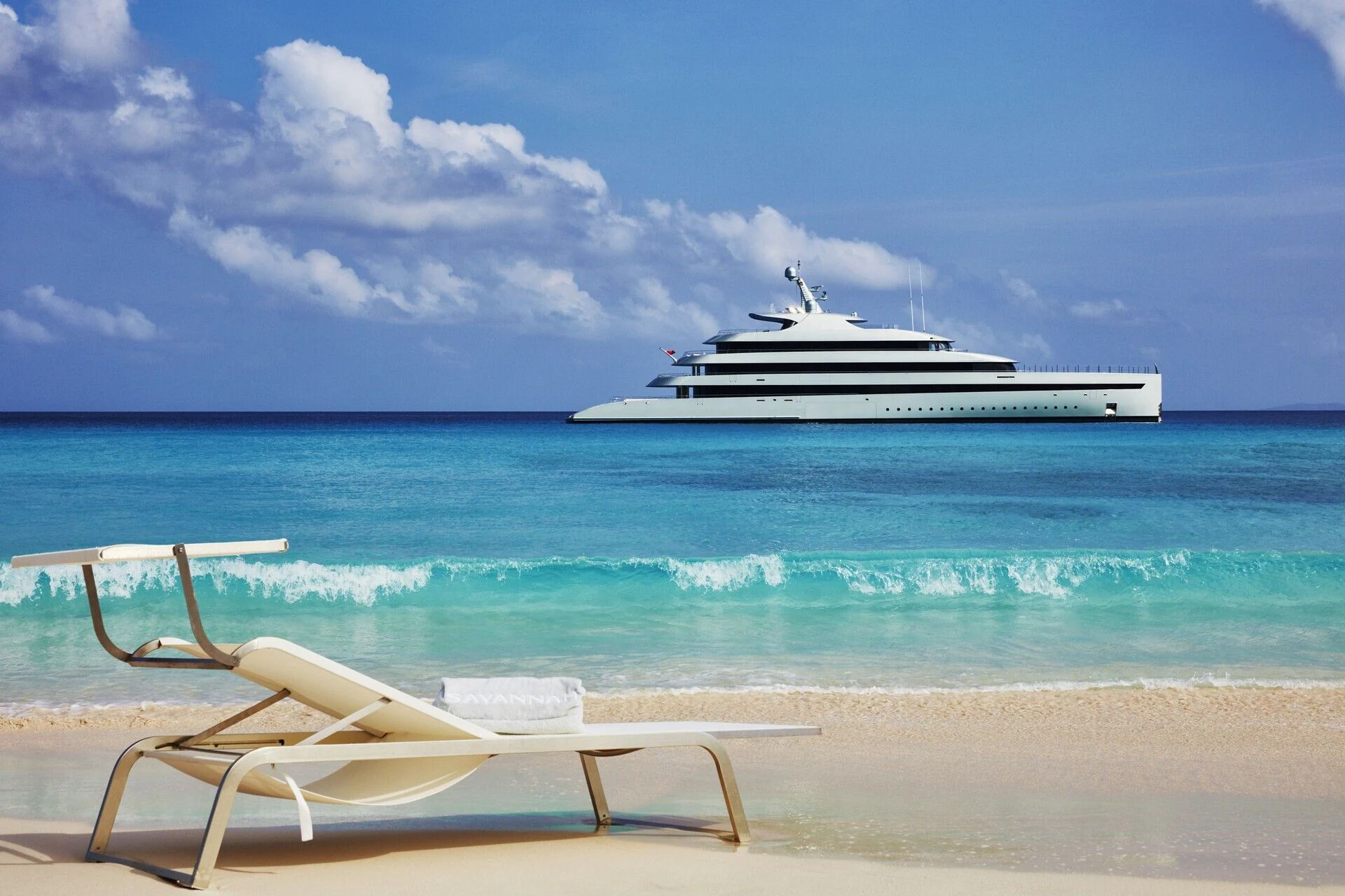 a chair on a beach with a boat in the background aboard SAVANNAH Yacht for Sale