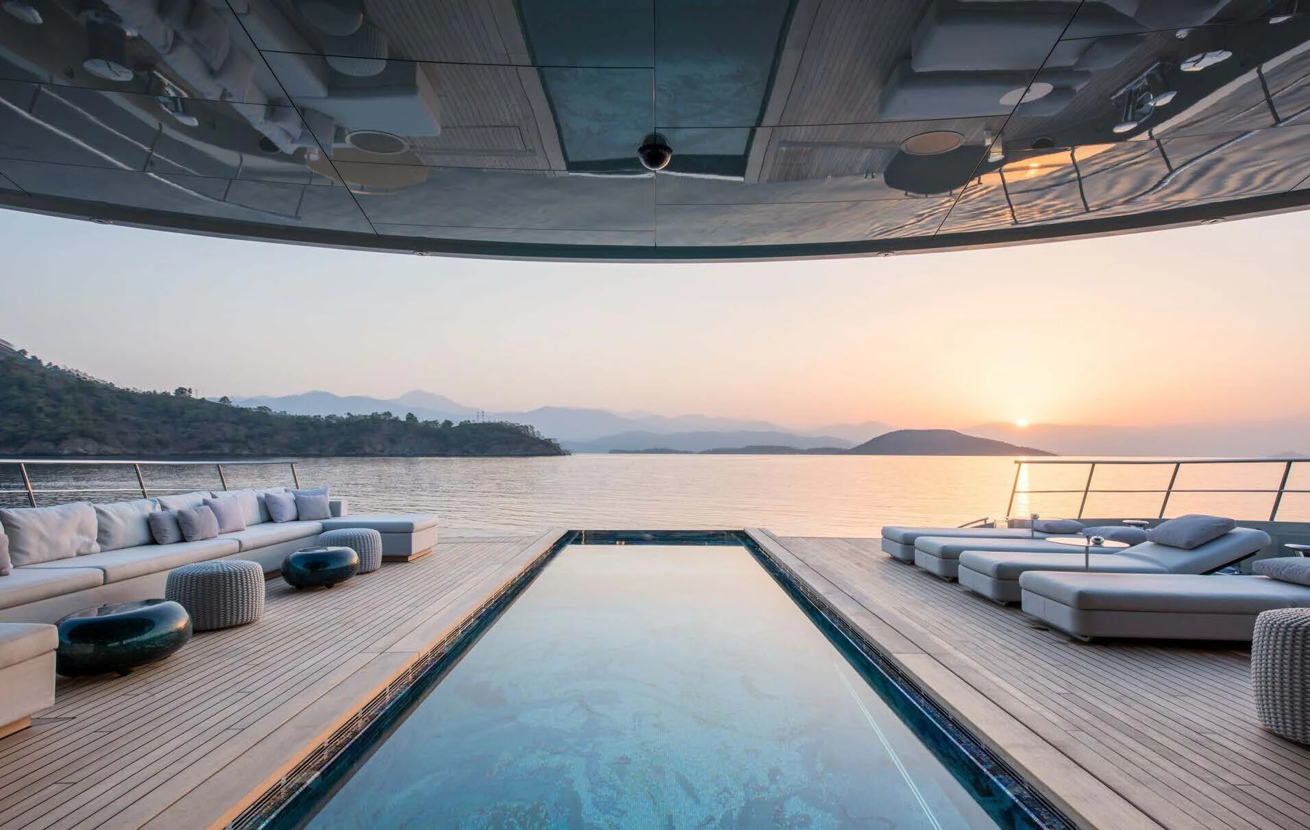 a large pool with a deck overlooking a beach aboard SAVANNAH Yacht for Sale