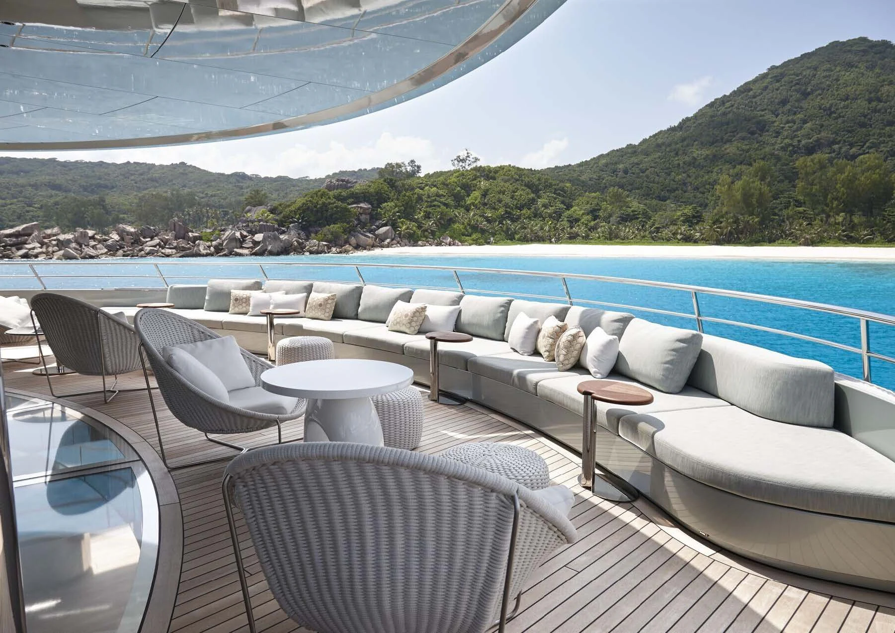 a patio with a pool and a deck with chairs and a large hill in the background aboard SAVANNAH Yacht for Sale