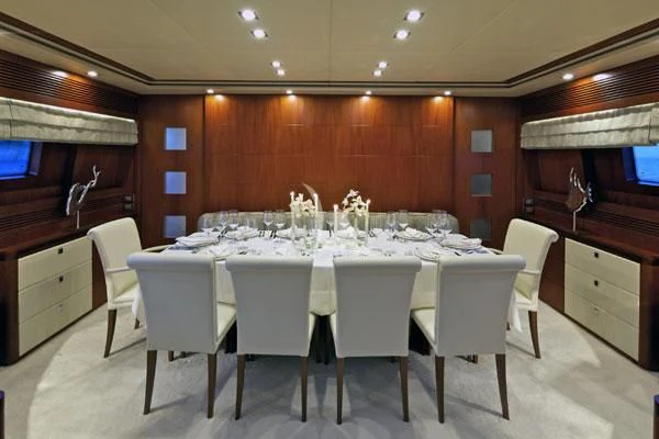 a large dining table with white chairs aboard BIANCA Yacht for Sale