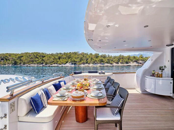 a table on a deck with a view of the water and the land below aboard BIANCA Yacht for Sale