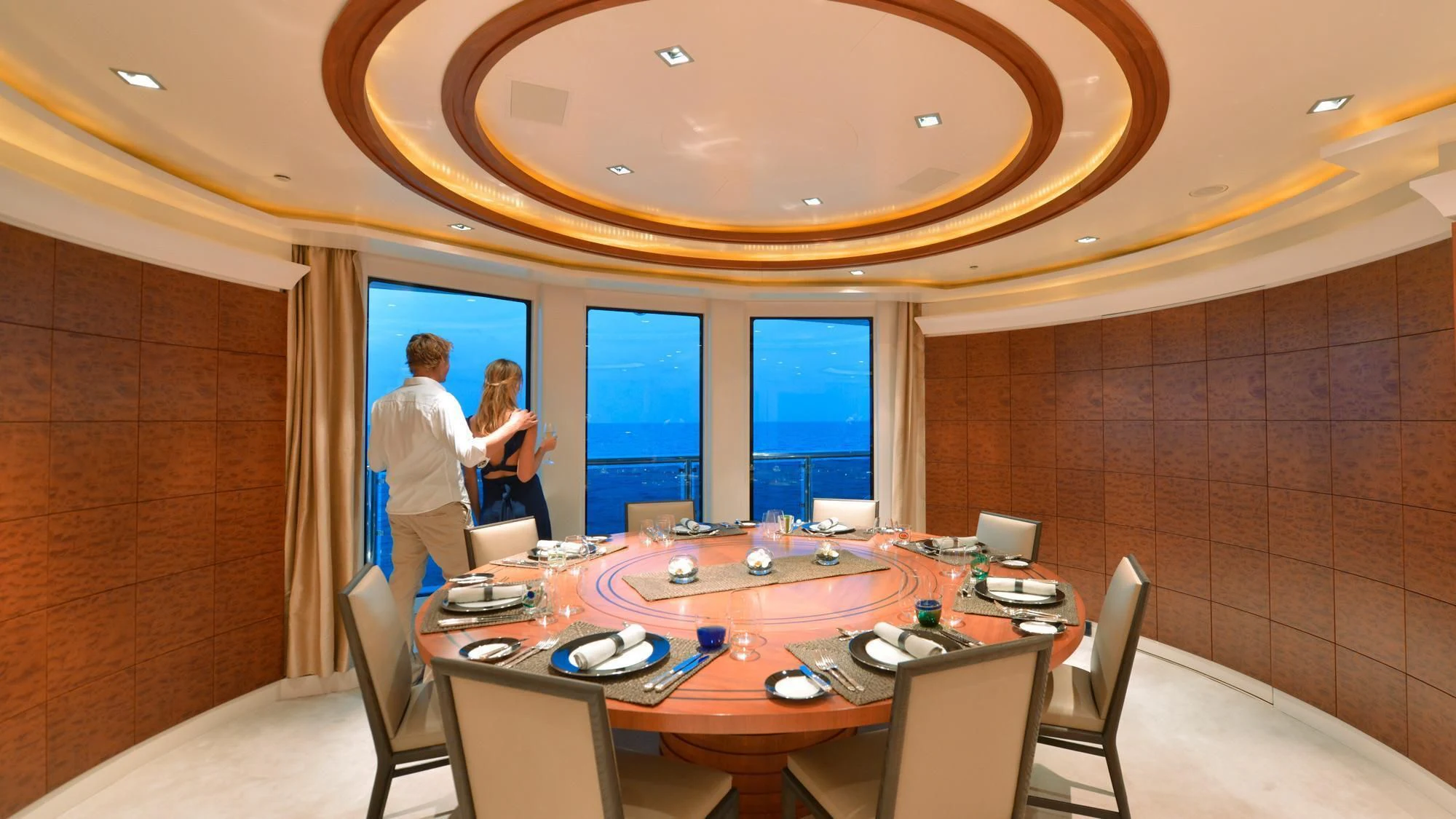 a man and woman standing in a room with a table and chairs aboard TRIPLE SEVEN Yacht for Sale