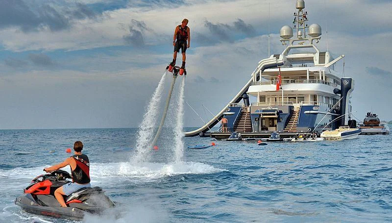 a boat with a water fountain and a boat in the background aboard TRIPLE SEVEN Yacht for Sale