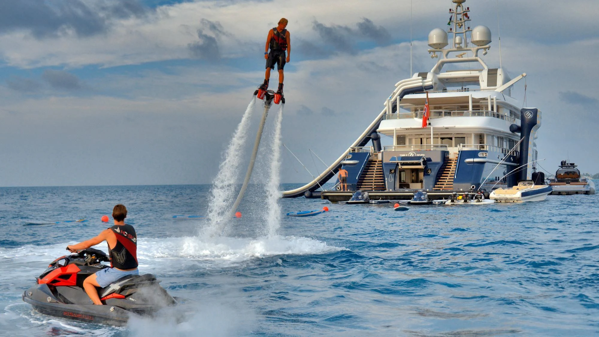 a boat with a water skier and a boat in the background aboard TRIPLE SEVEN Yacht for Sale